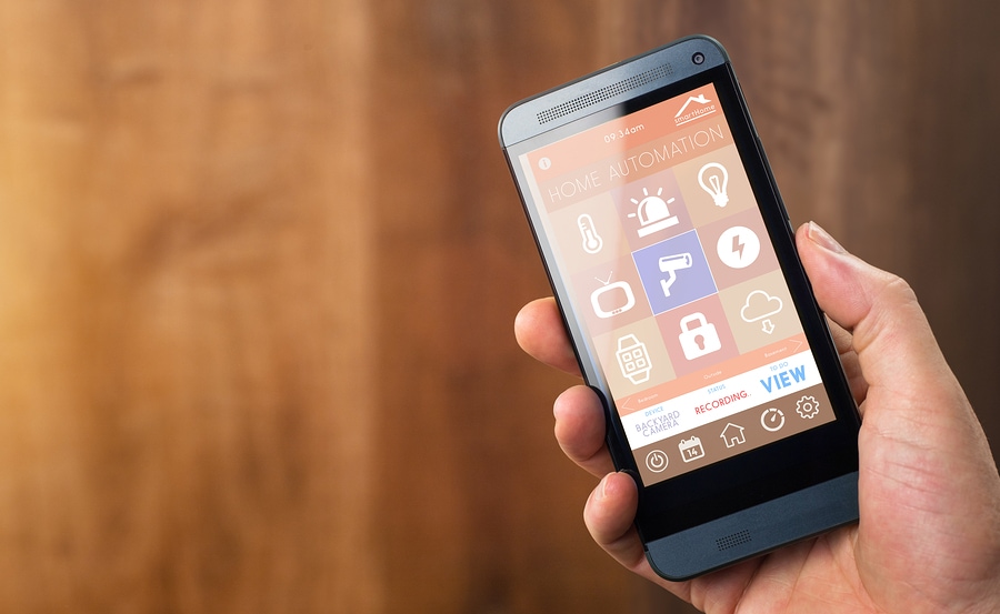 smart house home automation device with app icons. Man uses his smartphone with smarthome security app to unlock the door of his house.
