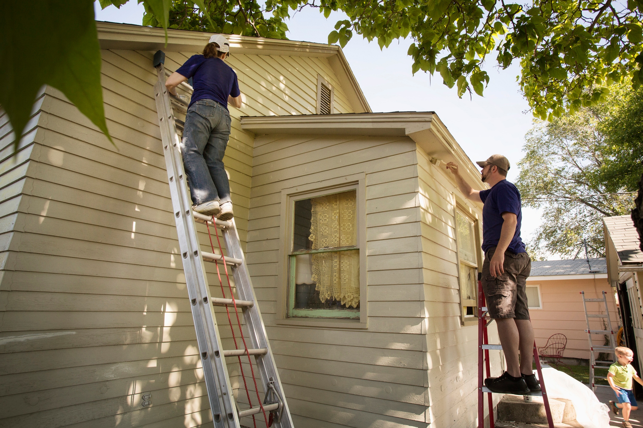 Men painting edge of house