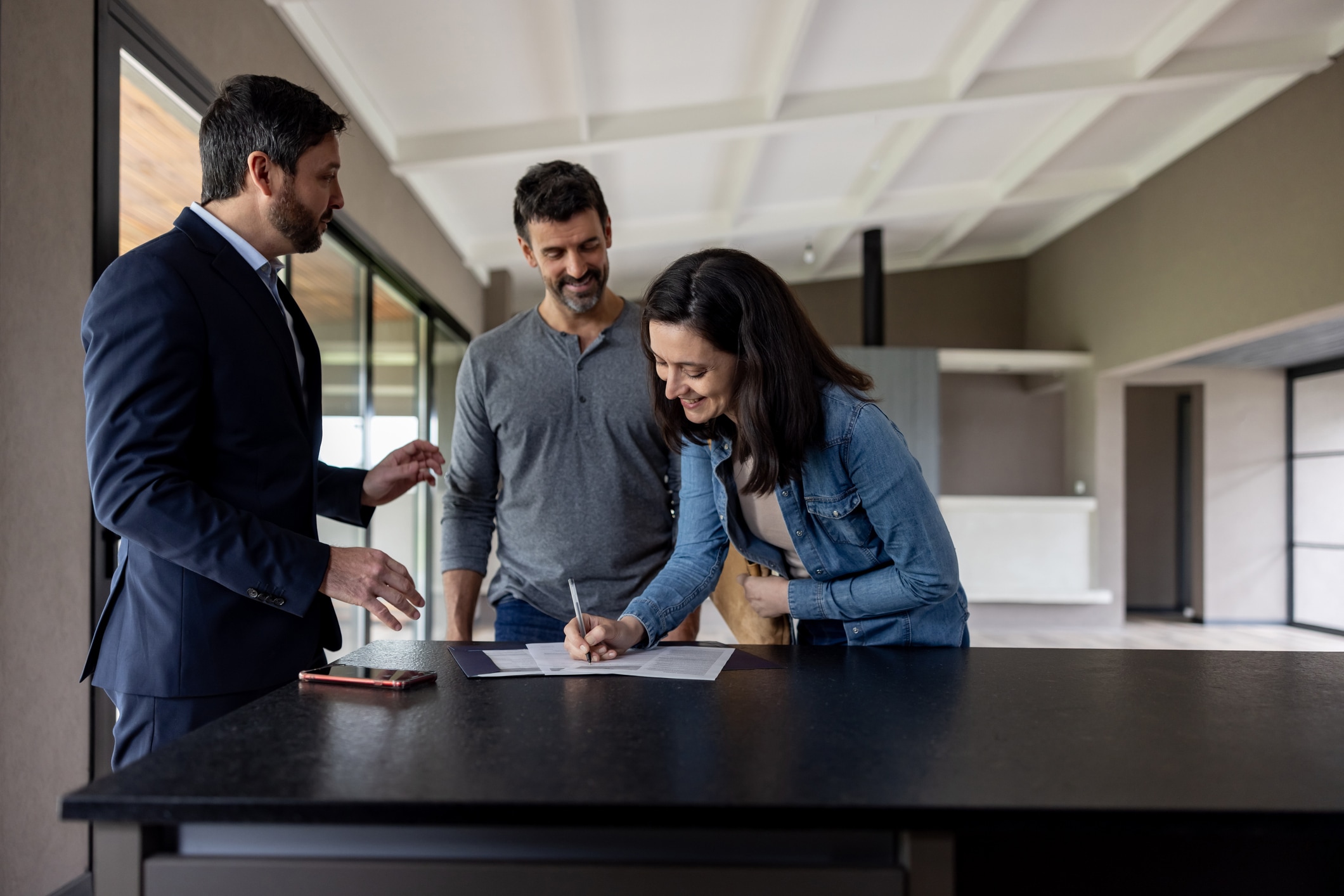 A couple buying a house and signing the deed in front of their real estate agent