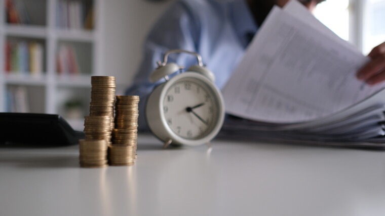 Businessman writing notes in documents model on stack of coins, in business, saving money