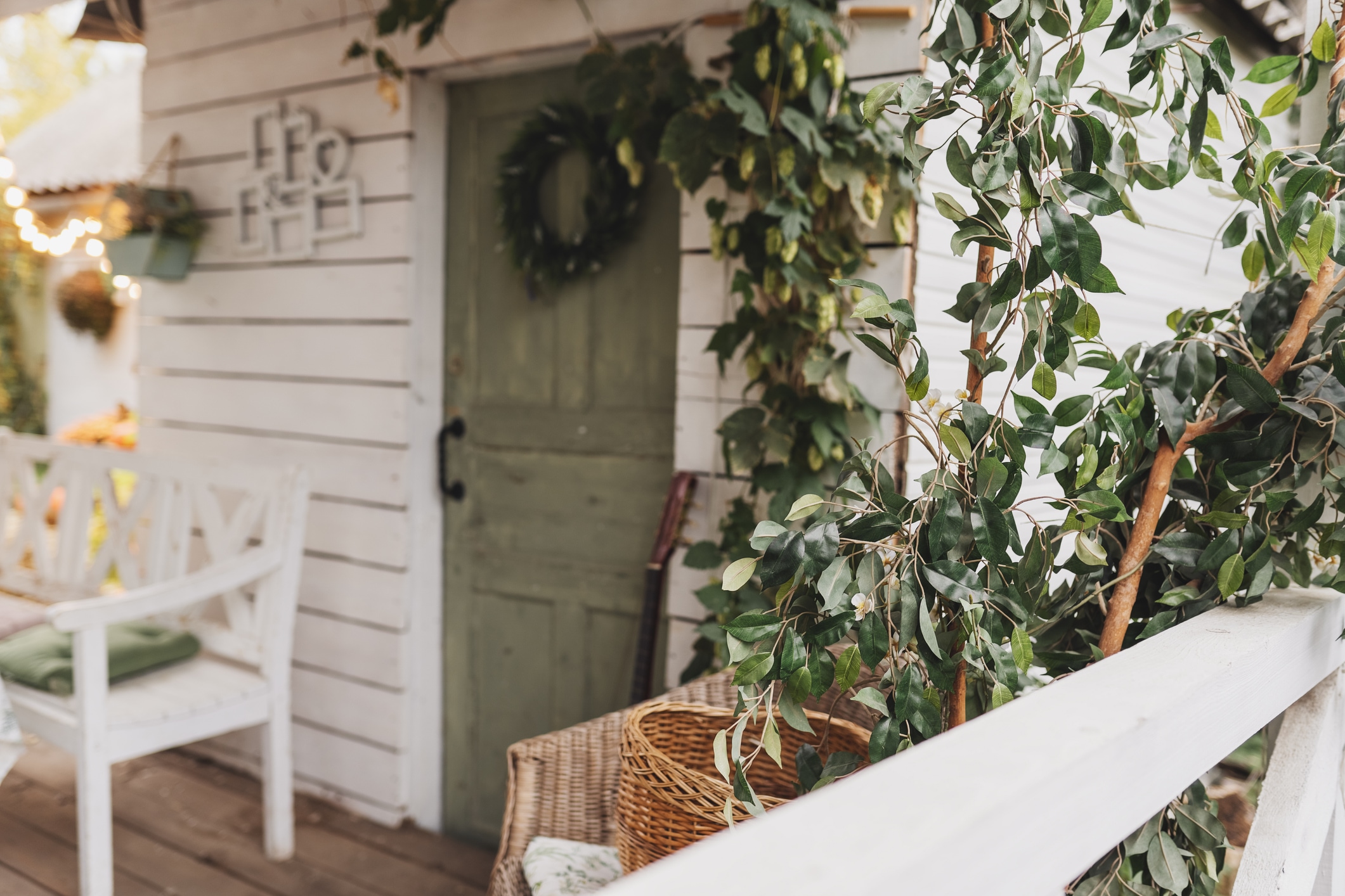 Beautiful porch home with autumn decorations on thanksgiving. Garden table and chairs with apples and pumpkins on autumn yard. Terrace with retro light bulbs garlands. halloween. Interior cozy patio