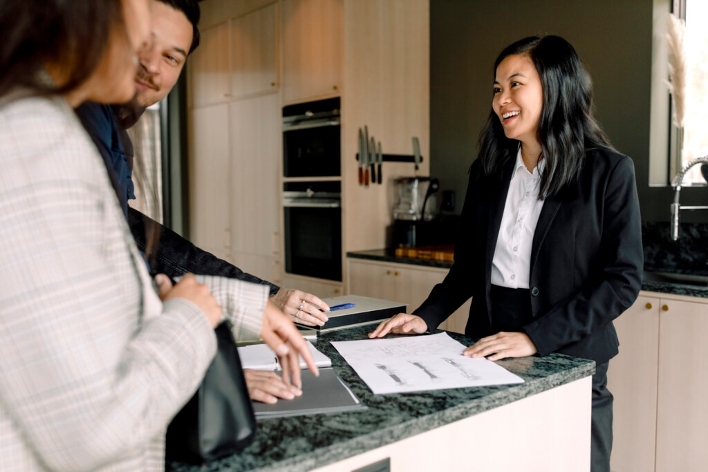 Smiling Real Estate Agent explaining documents of new house to clients.