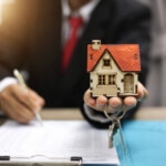 Businessman signs contract behind home architectural model