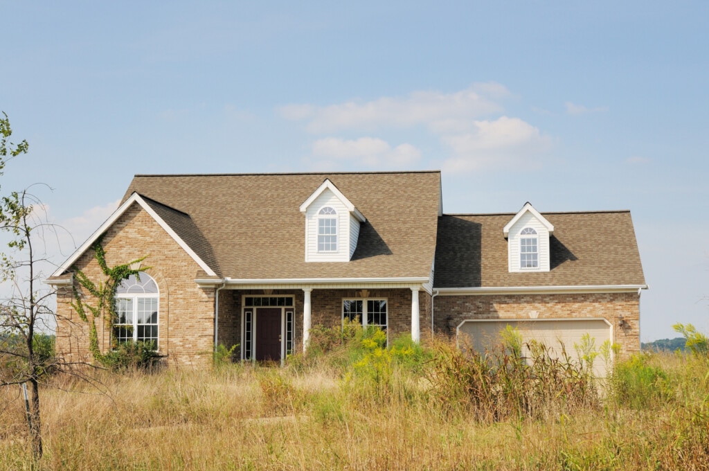 A foreclosure modern American home with an overgrown lawn